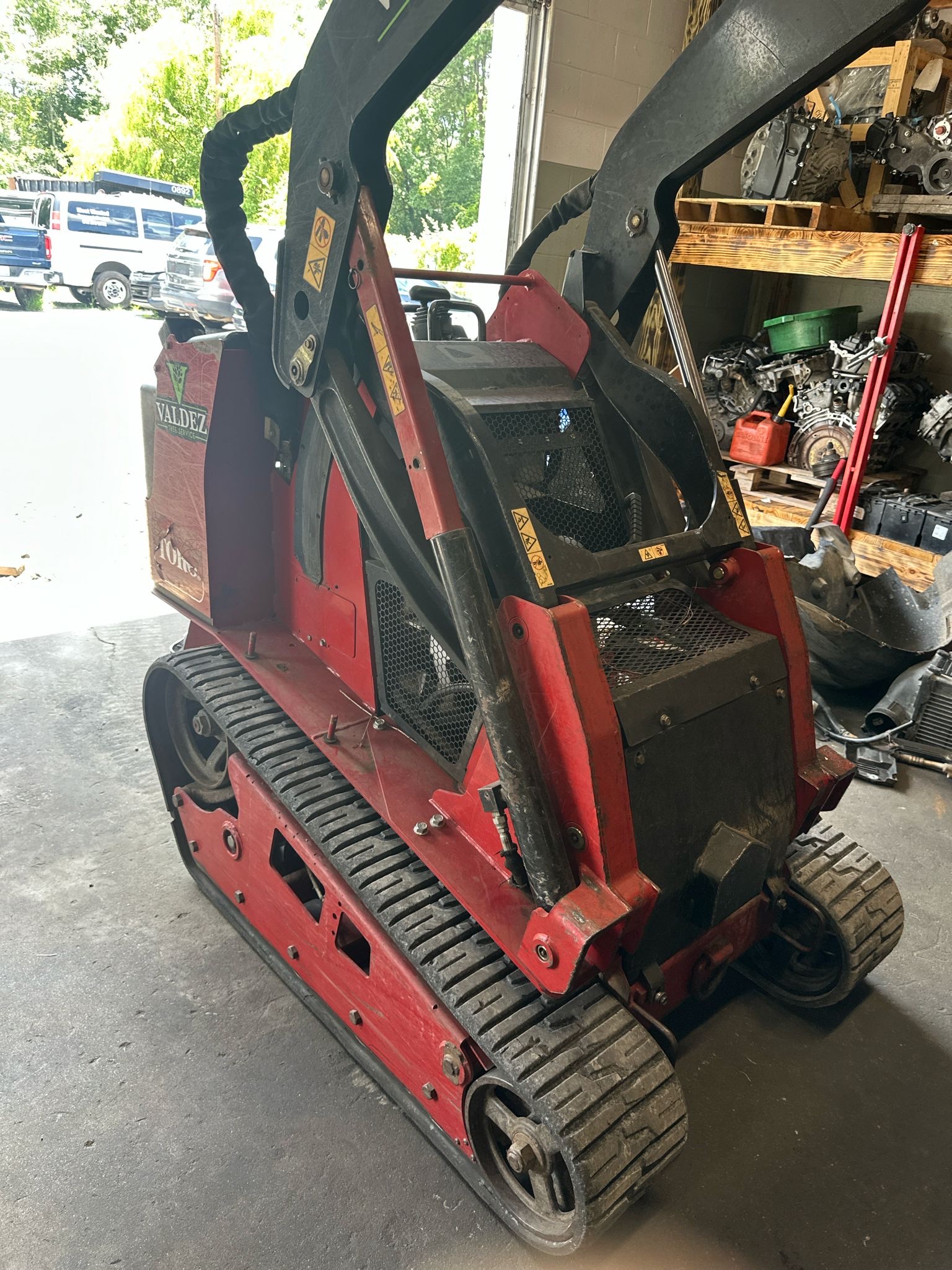 A compact tracked loader parked in our bay beside engine parts