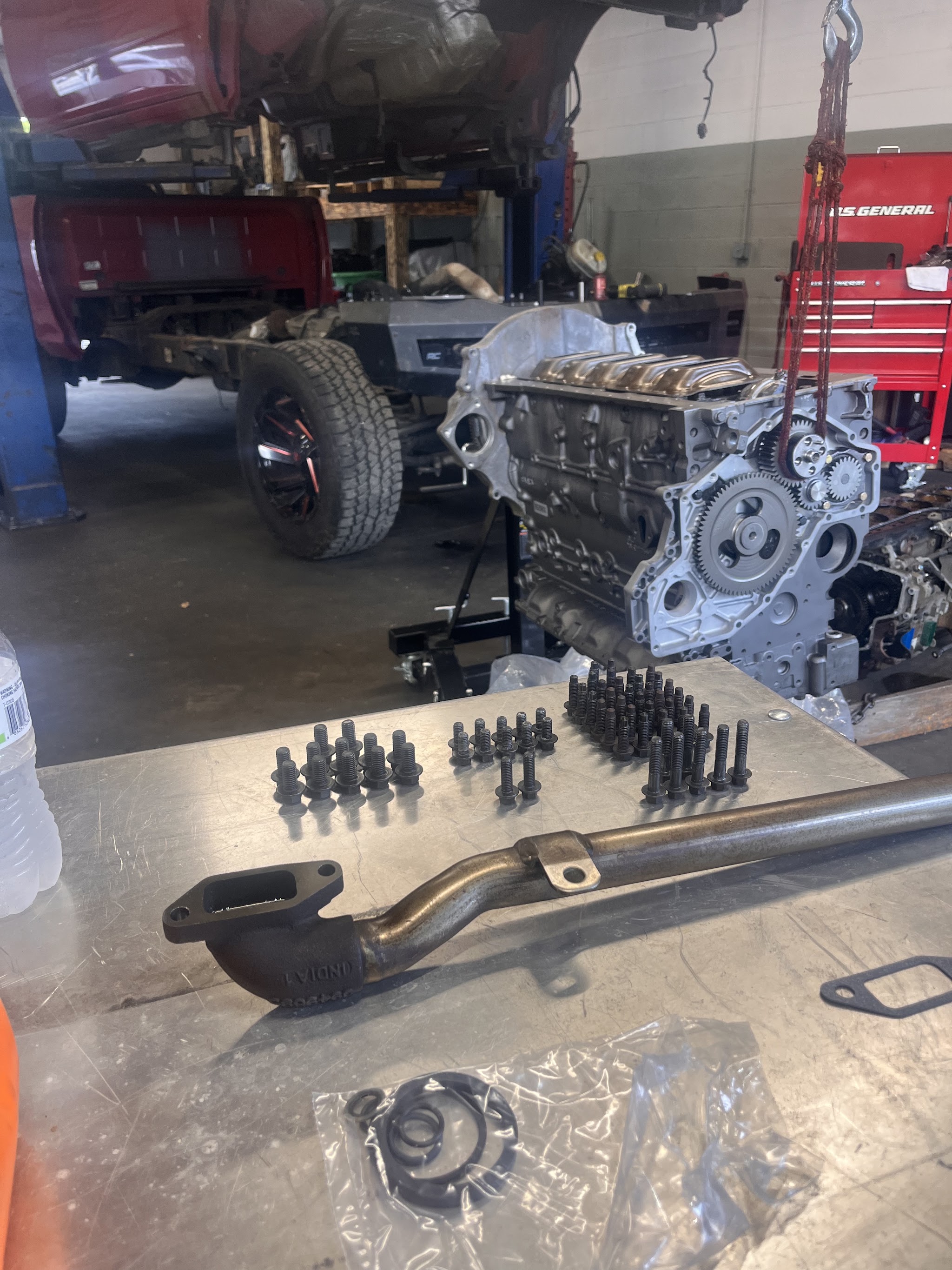 An engine block on a stand with bolts and parts laid out on the bench