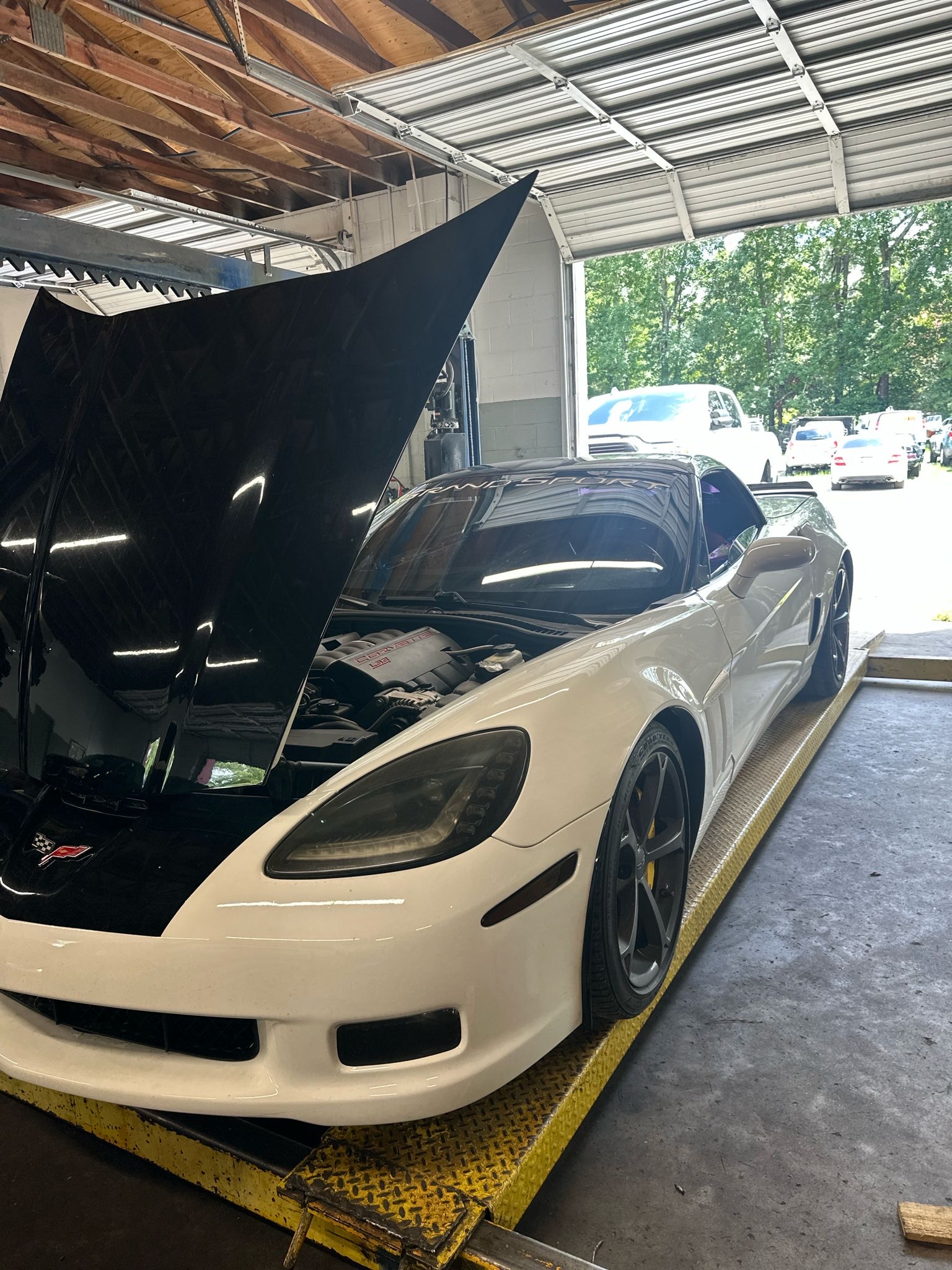 A white Corvette raised on our lift with the hood open